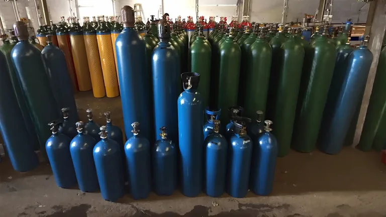 Stocked welding gas cylinders at the Northeast Gas & Ice fill yard — multiple cylinder sizes staged for cylinder exchange and delivery