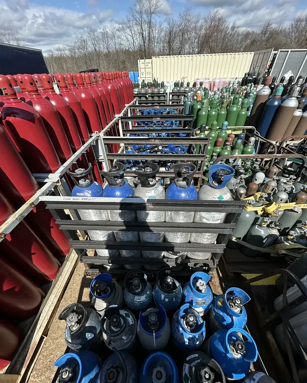 Cylinder yard at Northeast Gas & Ice — mixed industrial and welding gas cylinders staged for delivery across New England